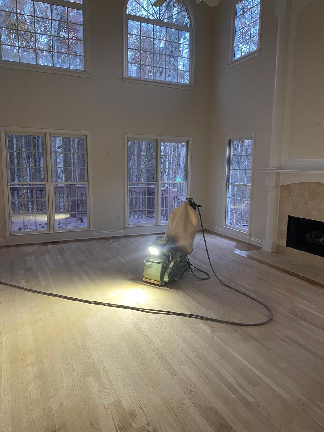 Hardwood floor being sanded in a large living room